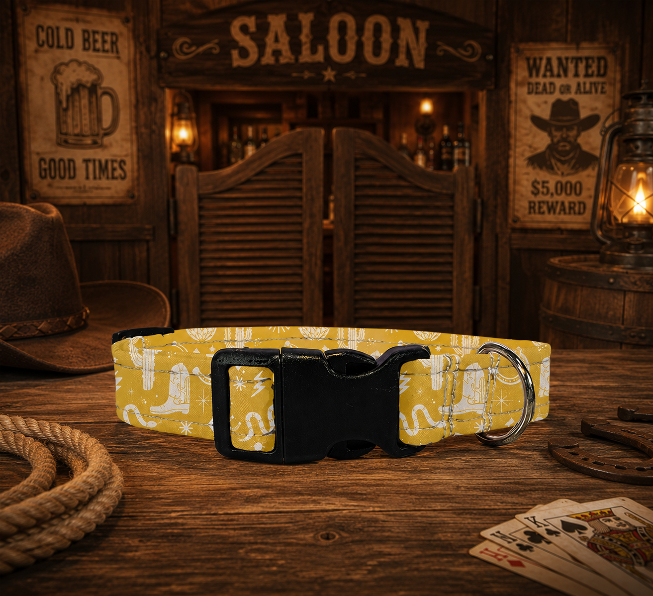 A yellow dog collar with a western boot and horseshoe pattern, featuring a black plastic quick-release buckle and a silver metal ring, displayed on a rustic wooden table with saloon-themed decor in the background.
